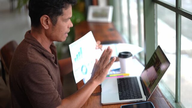 Asian Businessman Having Online Video Conference While Holding Business Planning Chart for Strategy Analysis