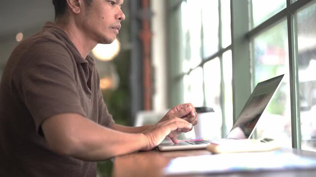 Young Man Working on Laptop Computer at Desk in Modern Office or Home Workspace, Using Technology for Online Business, Internet Research, and Digital Lifestyle Activities