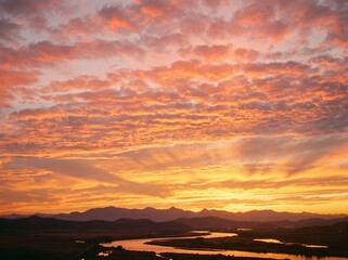 Fototapeta premium Vibrant Sunset Over a Winding River and Distant Mountains.