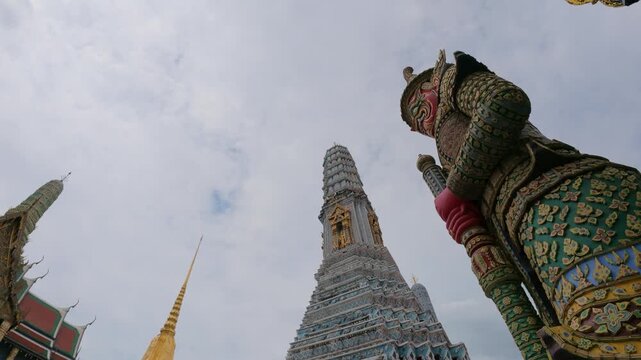 View of the ornate Yaksha guardian statue and the towering prang at The Grand Palace in Bangkok, Thailand.