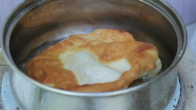 Chef deep frying traditional langos dough in hot oil