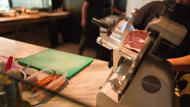Professional Chef Slicing Cured Meat with Electric Deli Slicer