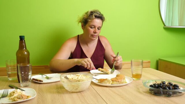 Woman eating a homemade stuffed cabbage roll, cutting bite-sized pieces with a knife and fork while enjoying lunch at home.
