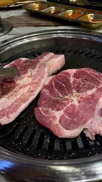 Sizzling Korean pork BBQ grilling on a hot tabletop pan in an authentic restaurant atmosphere.