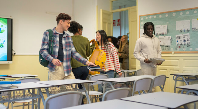Diverse young adult students walking into a bright classroom to attend a university lecture
