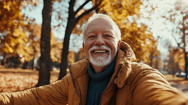 Joyful elderly man with open arms smiling in a vibrant autumn park setting