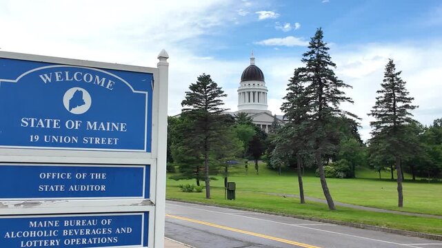 Maine State House dome with a welcome to Maine sign in the foreground