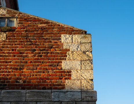 Detailed View of an Old Red Brick and Light Stone Masonry Wall Against a Clear Blue Sky
