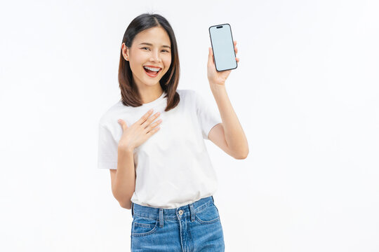 Happy young Asian woman holding a smartphone with blank screen and smiling on white studio background.