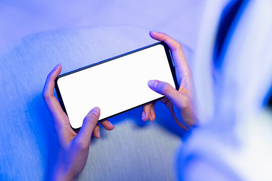 Hands holding smartphone with blank screen while playing mobile game, online gaming and digital entertainment concept.