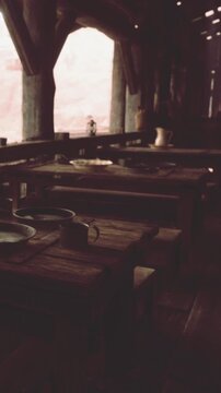 People are not in the room but wooden tables and chairs are set with dishes. Light comes through the windows creating a warm feel. The space seems quiet and inviting at dusk.