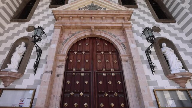 View of the ornate wooden entrance and patterned facade of the Catedral Basilica de la Inmaculada Concepcion in Mazatlan, Sinaloa, Mexico.