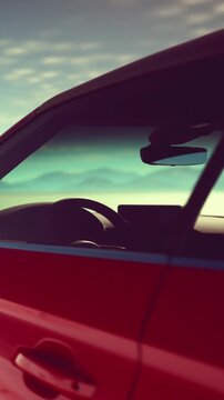 A red car is parked close to the beach. The sun is setting, and the colors in the sky are changing. The ocean can be seen in the distance.
