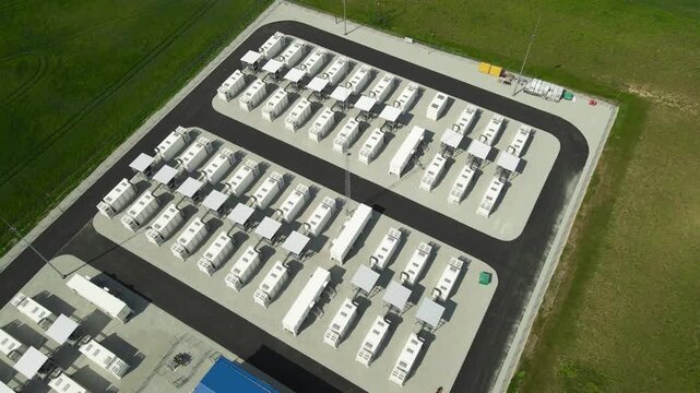 High angle drone shot flying over a modern BESS, a large scale battery energy storage system facility with lithium ion containers, supporting the transition to sustainable power generation