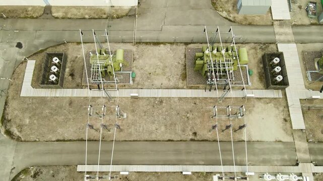 High voltage electrical substation with power lines, transformers, and insulators distributing electricity to a city, showing a top down view of the industrial energy generation complex