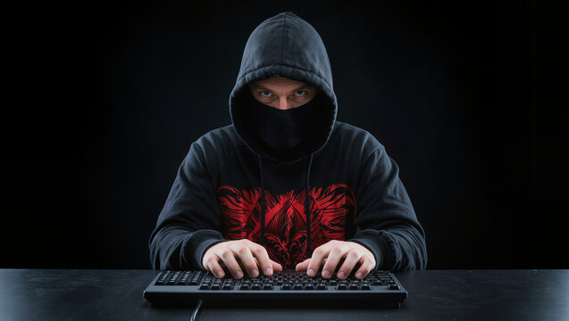 Front angle shot , a hacker in black hood with red pattern graphic on costune , in the black room.