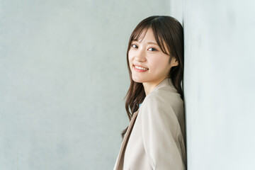 Fototapeta premium A smiling young Asian businesswoman in a gray-backed office building.