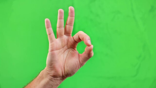 Close-up hand gesture forming OK sign with thumb and index finger, vibrant green background, symbolizing approval, success, and positive affirmation