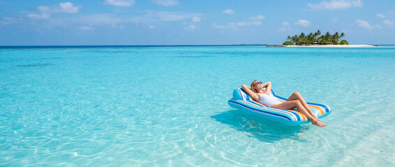 Obraz premium Woman relaxing on a floating air mattress in turquoise tropical ocean