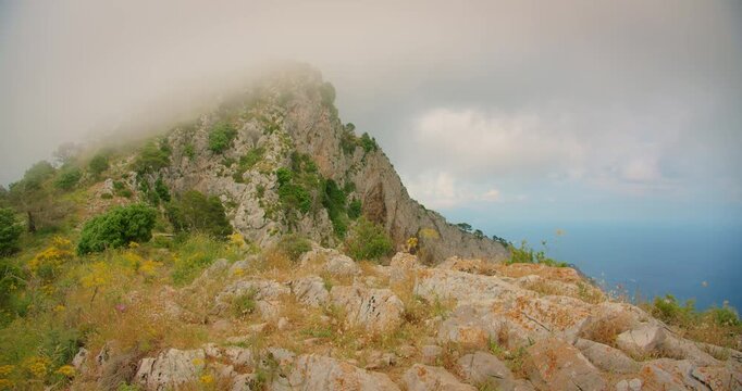 Rocky mountain peak of Monte Solaro with mist rolling over cliffs and sea view on Capri island