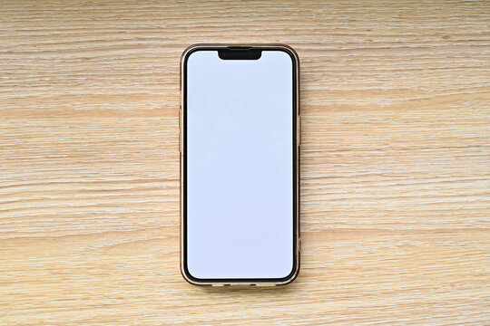 Smartphone with a blank screen isolated on a wooden table background. clipping path. white. copy space, empty, free, negative, text, design. Top view, flat lay, high angle, above.