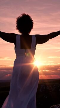 A Woman in a White Dress Embraces the Sunset, Radiating Joy and Serenity as She Stands on a Mountain, Capturing a Moment of Beauty and Freedom in Nature.