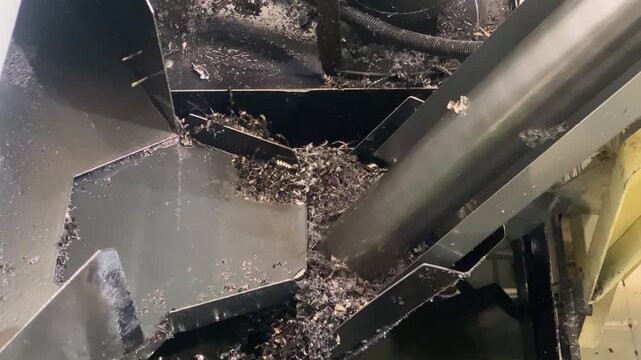 Close-up video of a screw conveyor metal scrap separator transporting metal chips away from a CNC machining center. The footage demonstrates automated chip removal, industrial waste h