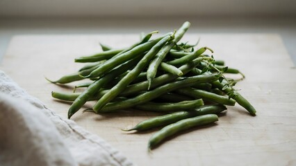 Fototapeta premium Fresh green string beans piled on wooden surface with cloth in background