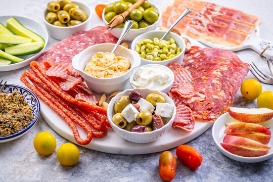 Gourmet charcuterie board with cured meats, olives, dips, and fresh fruit