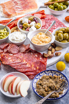 Gourmet charcuterie board with cured meats, olives, dips, and fresh fruit