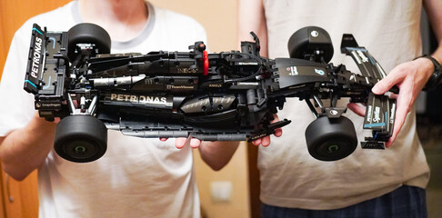 Obraz premium Turkey, June 30, 2025: Friends hold a completed scale model of a Mercedes-AMG F1 racing car, made from Lego Technic bricks. A close-up of the black brick with Petronas logos. 