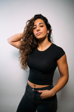 Confident young adult woman with curly hair posing