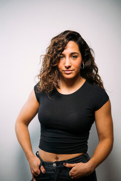 Confident young adult woman with curly hair standing