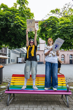 Activists holding equality placards on a rainbow bench