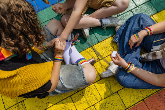 Friends sitting on a rainbow street with pride accessories