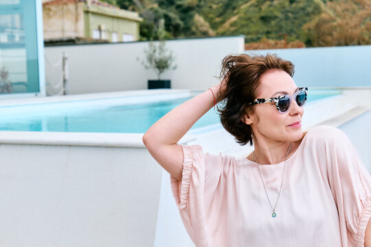 Happy woman relaxing by the pool in pink outfit