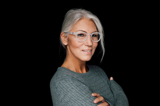 Portrait of smiling woman wearing glasses in front of black background