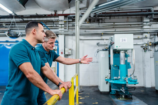 Male technicians discussing while working in factory