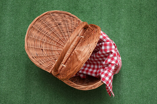 Rattan picnic basket with napkin on green background