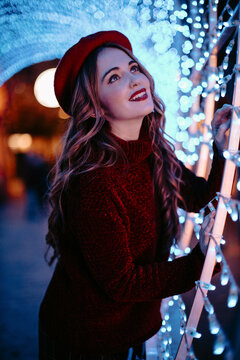 Smiling in red beret under glowing holiday winter light at night