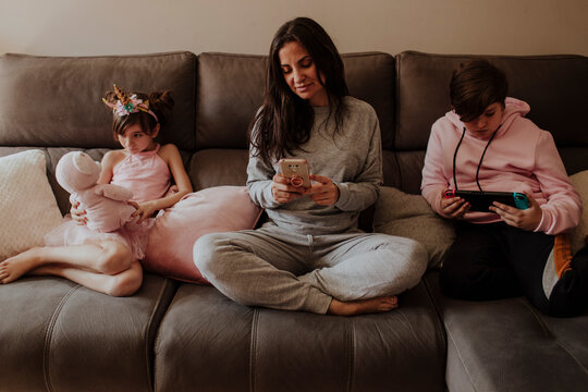 Mother and family using technology on sofa at home
