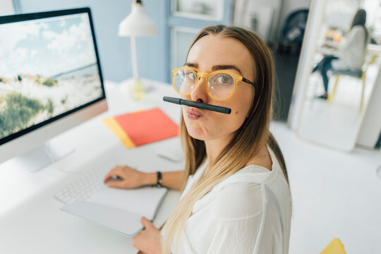 Portrait of funny young woman at desk pouting mouth