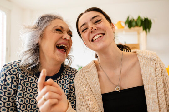 Happy mature woman with daughter having fun at home