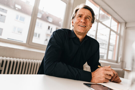Smiling mature businessman at table in office