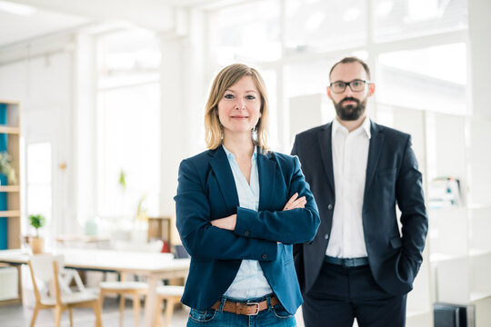 Portrait of confident businesswoman and man in office