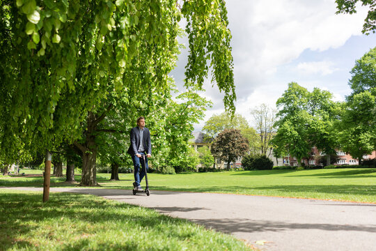 Businessman using E-Scooter in a park