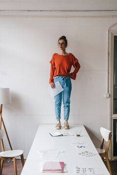 Young woman standing on table thinking