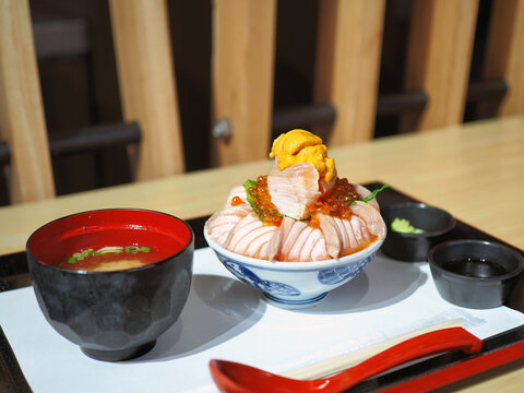Bowl of loaded sliced grilled Salmon or aburi sashimi top with salmon roe, fresh uni and oba leaf.