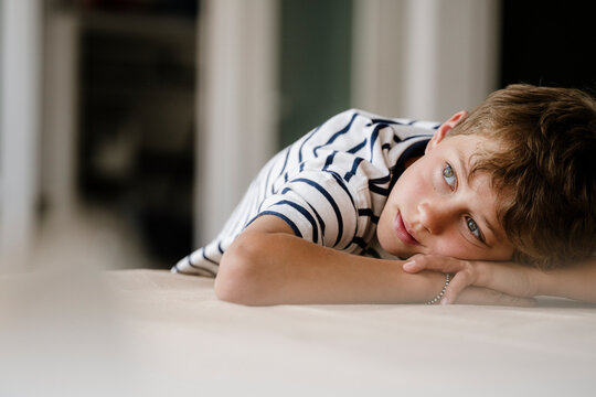 Pensive boy relaxing and daydreaming indoors