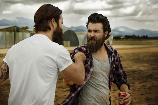 wo men with full beards fighting in abandoned landscape